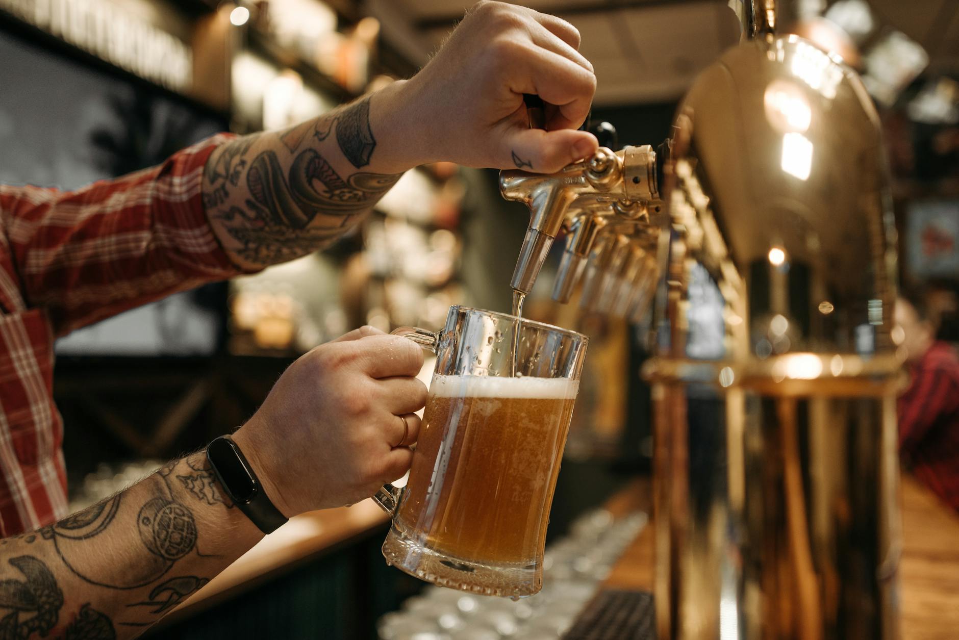 bartender pouring beer into pint glass